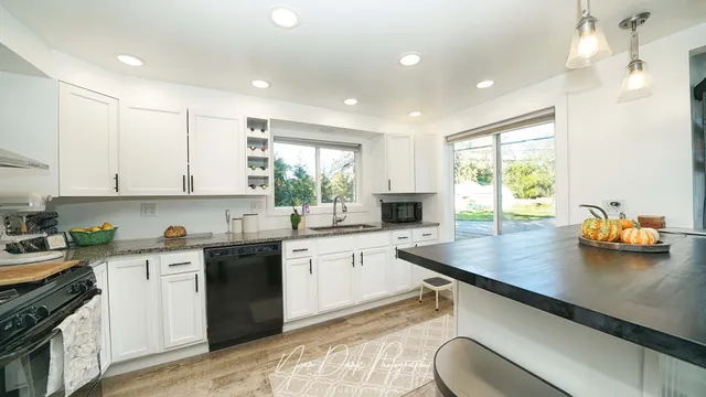 a kitchen with stainless steel appliances granite countertop a sink window and cabinets