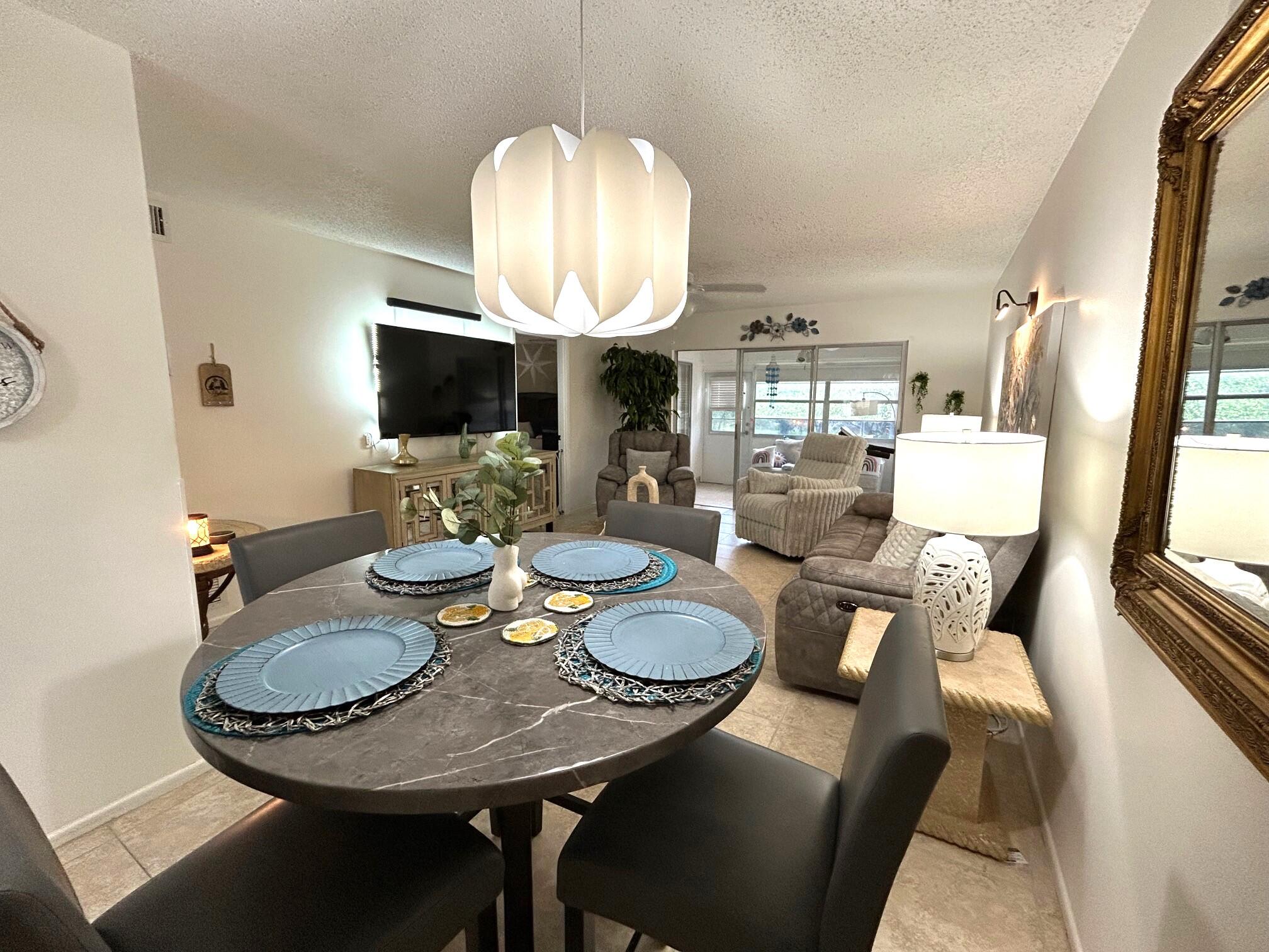255 Down E Lane, Unit B Lake Worth, FL 33467 - Photo 8 of 31 a view of a dining room with furniture a chandelier and wooden floor