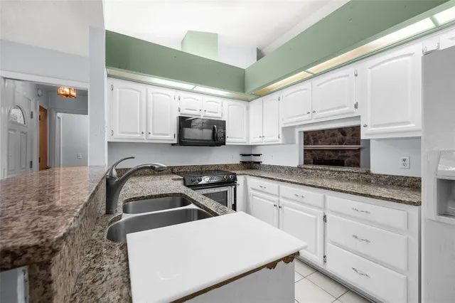 a kitchen with granite countertop white cabinets and stainless steel appliances