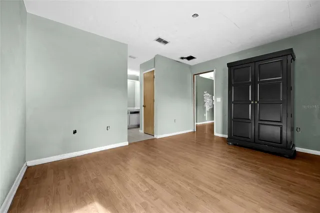 a view of an empty room with wooden floor and closet