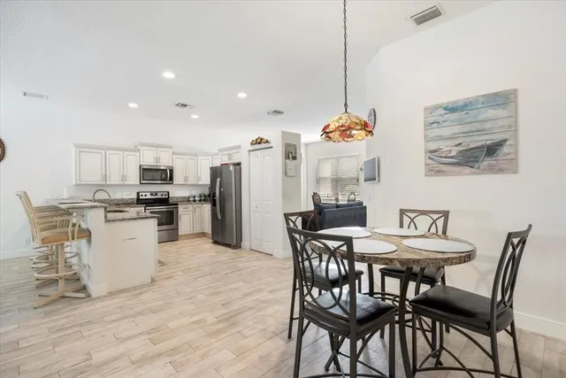 a dining room with stainless steel appliances kitchen island granite countertop a dining table chairs and a white refrigerator