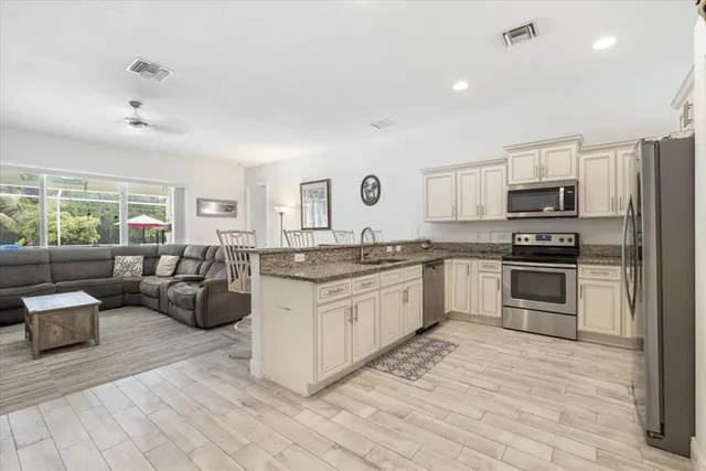 a large kitchen with granite countertop a stove top oven a sink dishwasher a dining table and chairs with wooden floor