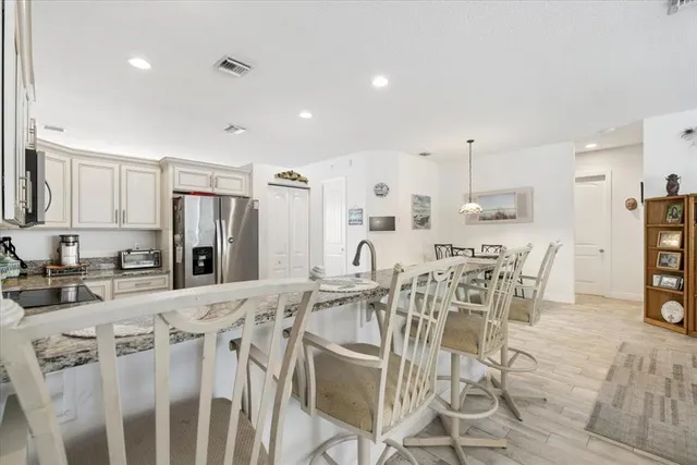 a kitchen with stainless steel appliances kitchen island granite countertop a table chairs and a refrigerator