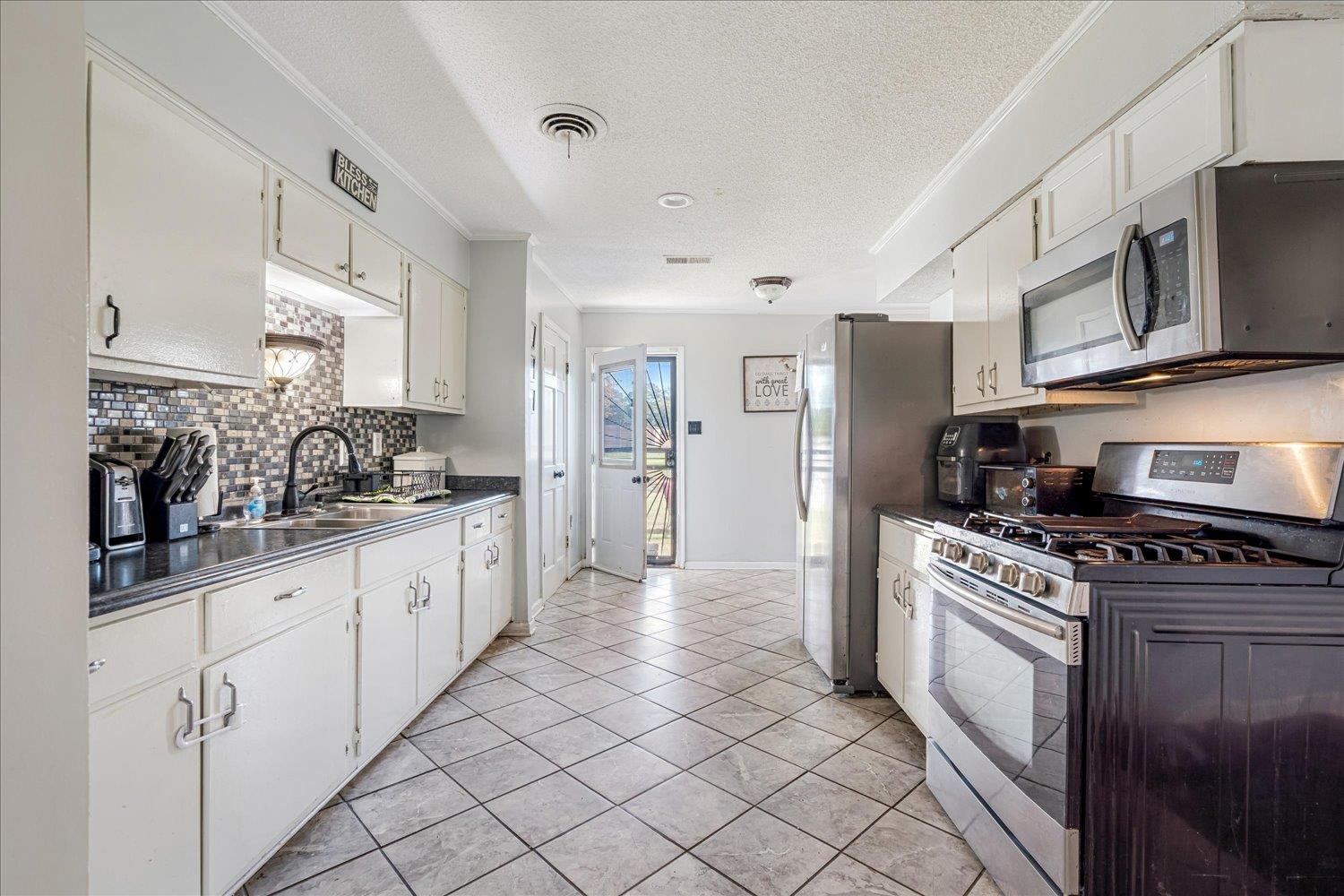 4340 Bluebell Street Memphis, TN 38109 - Photo 14 of 29 a kitchen with stainless steel appliances granite countertop a stove a sink and a refrigerator
