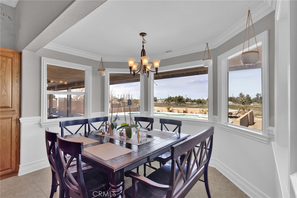 12290 Larch Road Oak Hills, CA 92344 - Photo 26 of 75 a dining room with furniture large windows and a chandelier