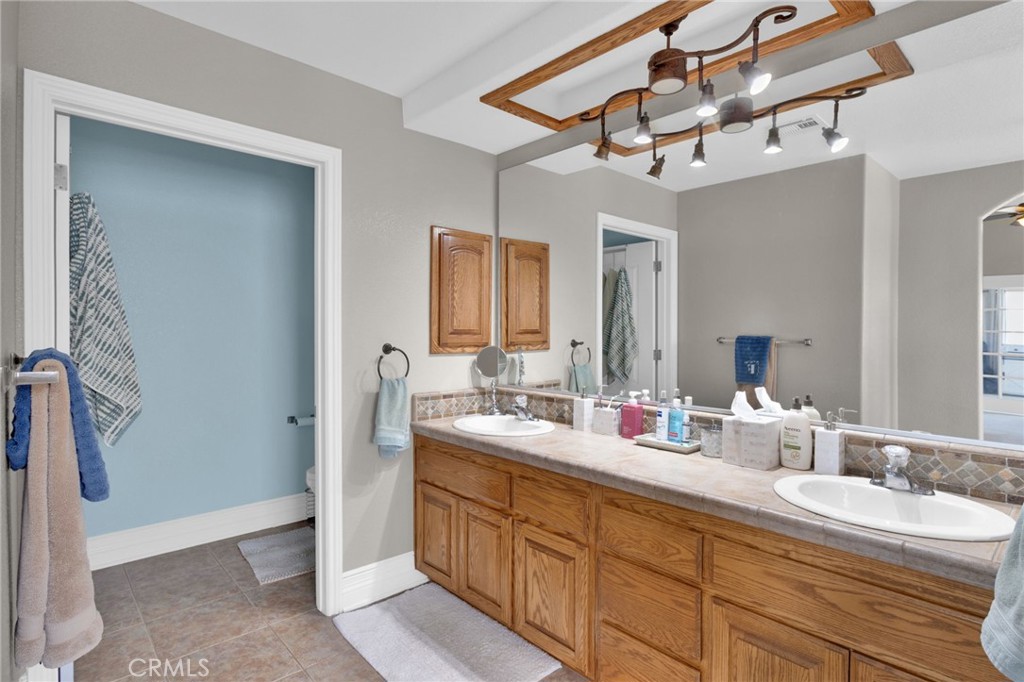 12290 Larch Road Oak Hills, CA 92344 - Photo 35 of 75 a bathroom with a double vanity sink and a mirror