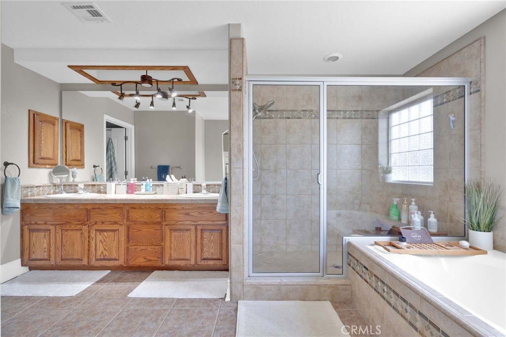 12290 Larch Road Oak Hills, CA 92344 - Photo 36 of 75 a spacious bathroom with a sink a mirror and a shower