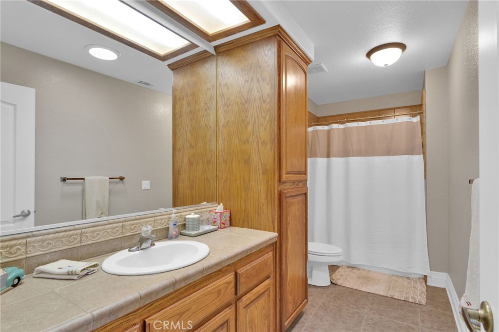 12290 Larch Road Oak Hills, CA 92344 - Photo 47 of 75 a bathroom with a granite countertop sink and a mirror