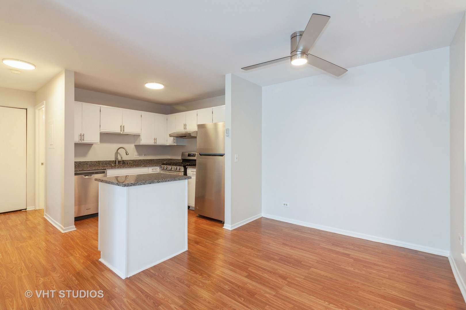 1352 McDowell Road, Unit 103 Naperville, IL 60563 - Photo 5 of 12 a kitchen with a refrigerator and white cabinets with wooden floor