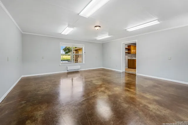 an empty room with a chandelier fan and windows
