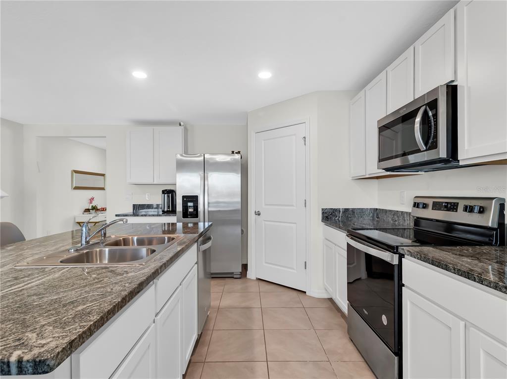 5446 Logan Cave Avenue Wimauma, FL 33598 - Photo 12 of 57 a kitchen with stainless steel appliances granite countertop a sink stove and refrigerator