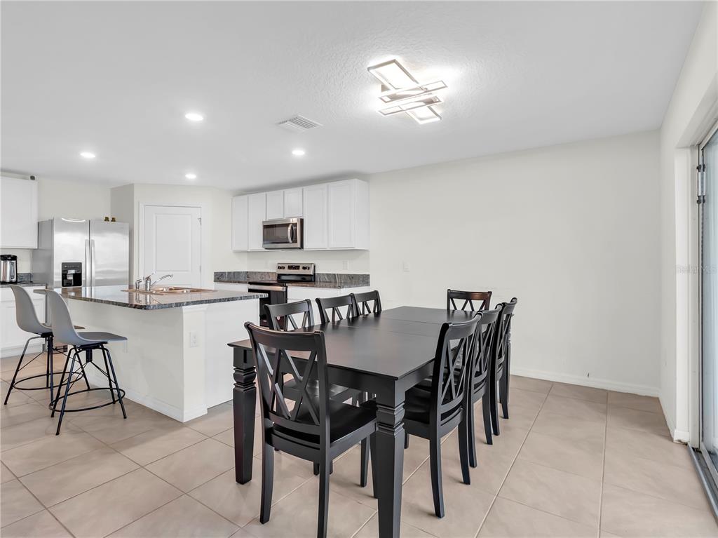 5446 Logan Cave Avenue Wimauma, FL 33598 - Photo 19 of 57 a dining area with stainless steel appliances a table and chairs
