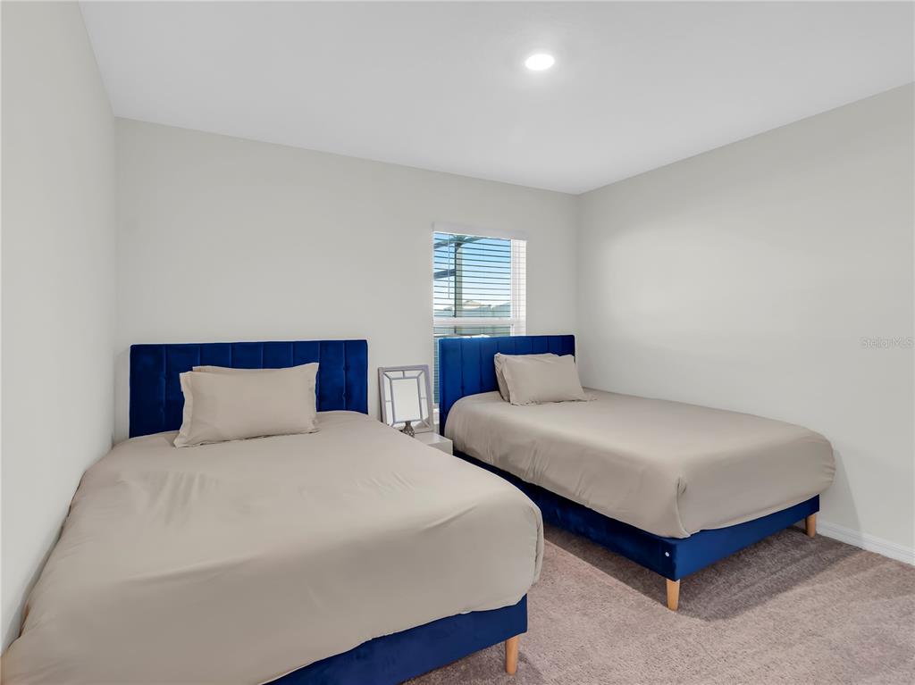 5446 Logan Cave Avenue Wimauma, FL 33598 - Photo 23 of 57 a bedroom with two beds and a lamp