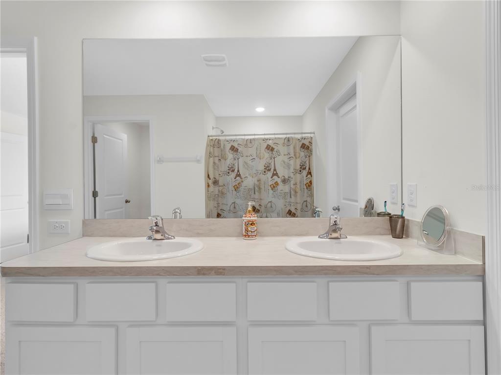 5446 Logan Cave Avenue Wimauma, FL 33598 - Photo 35 of 57 a bathroom with double vanity sinks and a mirror