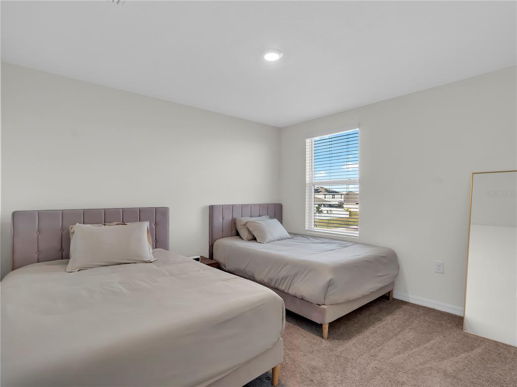 5446 Logan Cave Avenue Wimauma, FL 33598 - Photo 39 of 57 a bedroom with two bed and a night stand