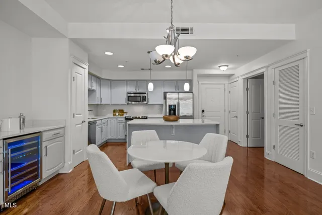 a view of a dining room and livingroom with furniture wooden floor kitchen view and a chandelier