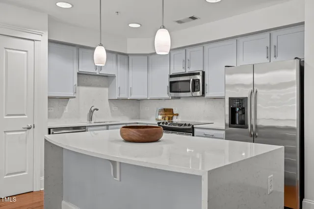 a kitchen with stainless steel appliances a sink a stove a refrigerator and cabinets