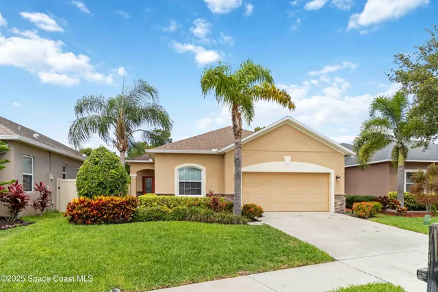 a front view of a house with a garden and palm tree