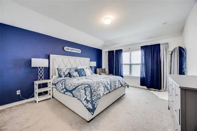 a bed sitting in a spacious bedroom next to a window and a flat screen tv