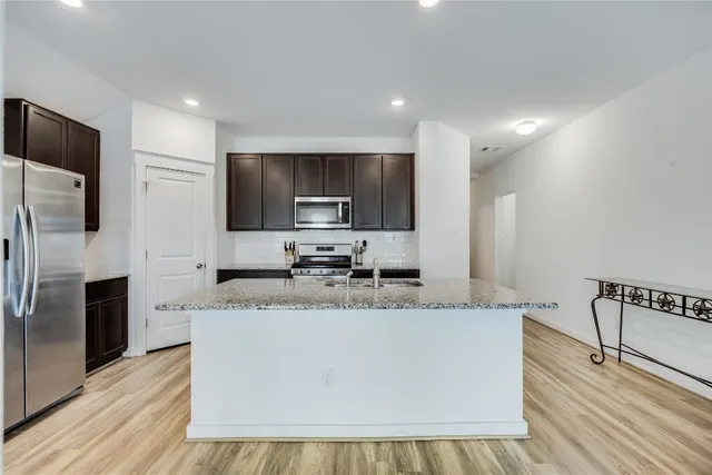 a large kitchen with stainless steel appliances granite countertop a stove a sink and a microwave