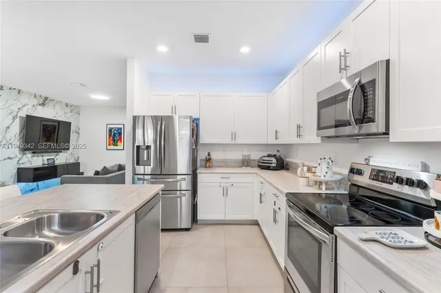 a kitchen with stainless steel appliances granite countertop a sink a stove and a refrigerator