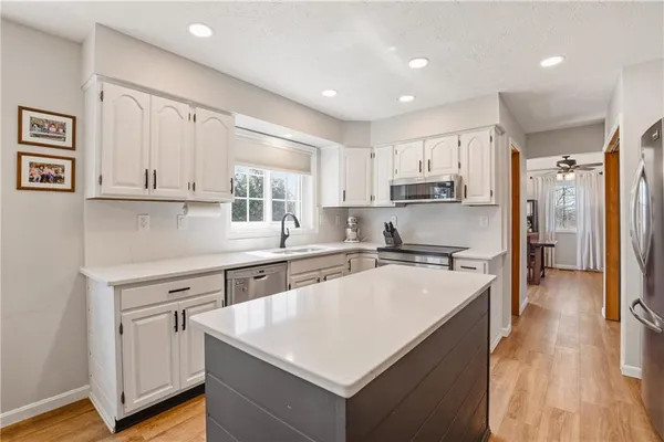 a kitchen with kitchen island white cabinets appliances and a center island