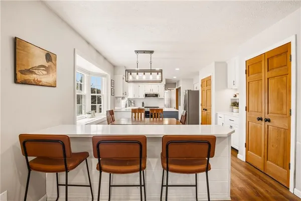 a kitchen with stainless steel appliances granite countertop a dining table chairs and a refrigerator