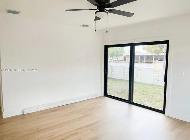 an empty room with wooden floor fan and windows