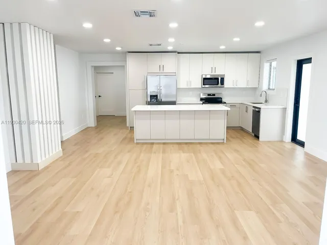 a large kitchen with stainless steel appliances a large counter top a stove and a refrigerator