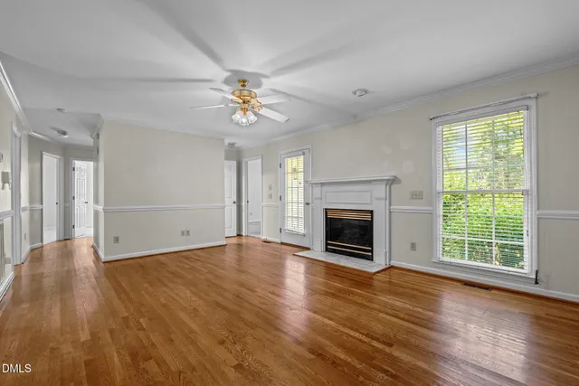 an empty room with windows fireplace and wooden floor