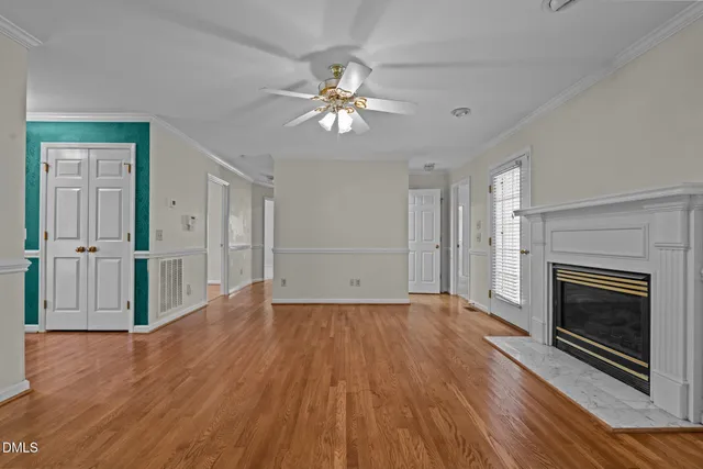 an empty room with wooden floor fireplace and windows