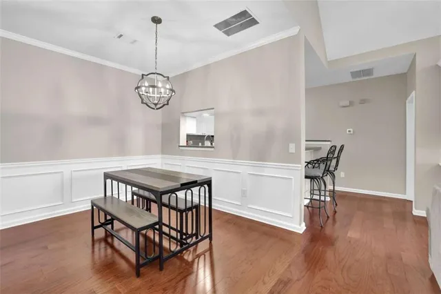 a dining room with wooden floor a chandelier a wooden table and chairs