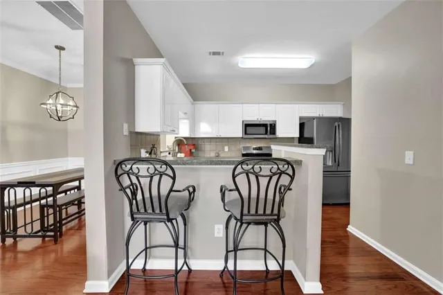 a kitchen with stainless steel appliances granite countertop a dining table chairs microwave and cabinets