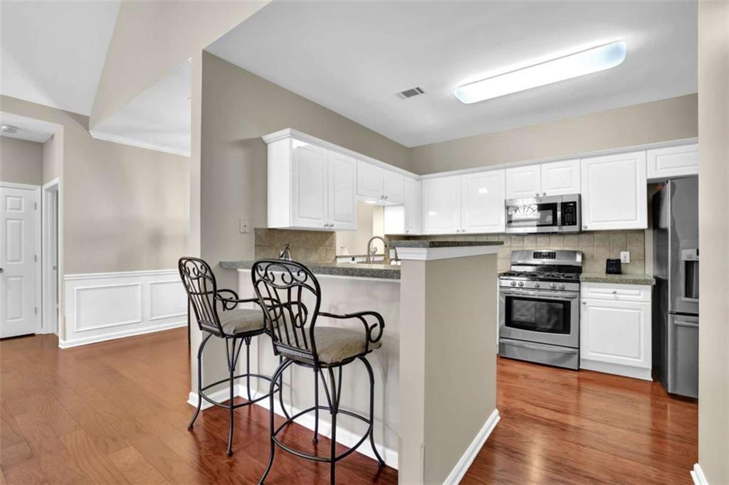 140 Stonegate Lane Canton, GA 30114 - Photo 16 of 38 a kitchen with stainless steel appliances granite countertop a stove top oven a refrigerator a dining table and chairs with wooden floor
