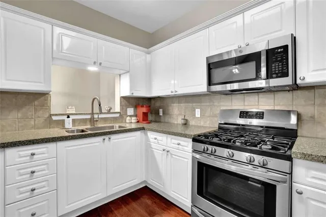 a kitchen with stainless steel appliances granite countertop grey cabinets a sink and a stove
