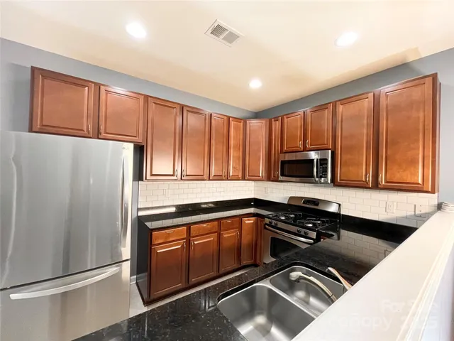 a kitchen with a refrigerator a sink a stove and cabinets