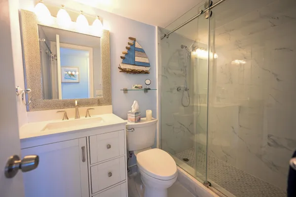 a bathroom with a granite countertop sink toilet a mirror a vanity and shower