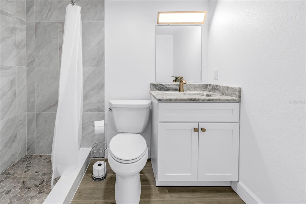 8630 Blind Pass Road, Unit 12 St. Pete Beach, FL 33706 - Photo 18 of 30 a bathroom with a granite countertop toilet a sink and a mirror