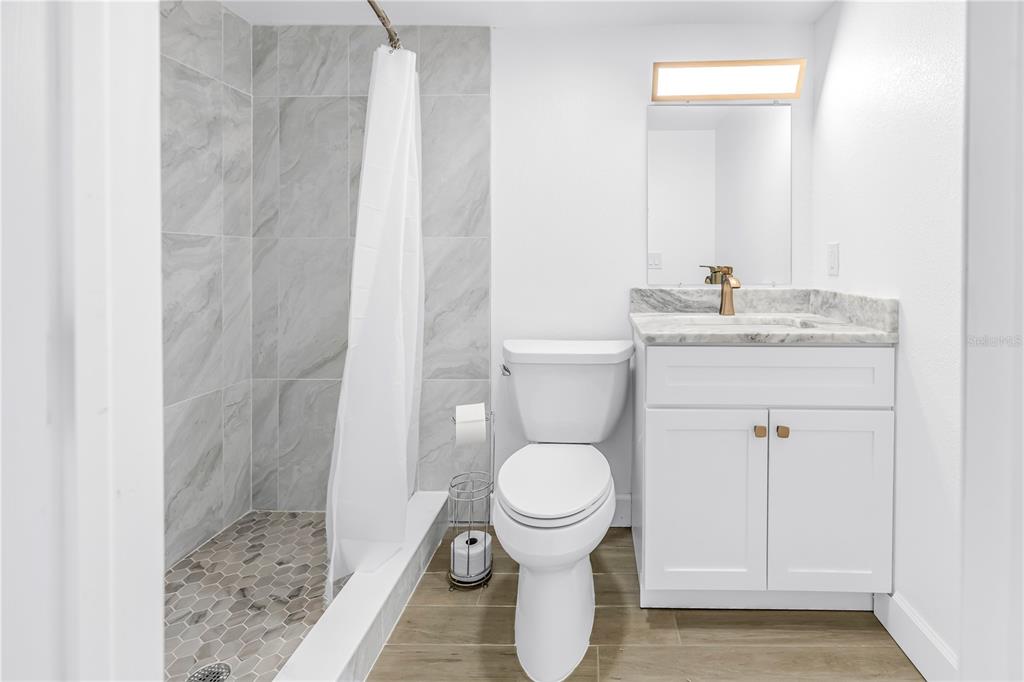 8630 Blind Pass Road, Unit 12 St. Pete Beach, FL 33706 - Photo 19 of 30 a bathroom with a granite countertop toilet a sink and a mirror