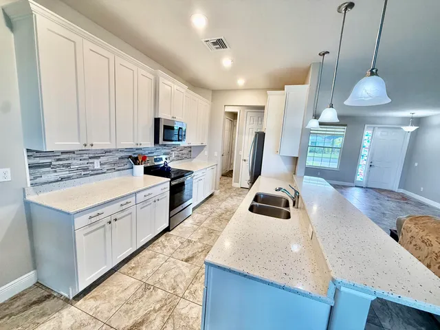a kitchen with kitchen island granite countertop a sink a counter space appliances and cabinets