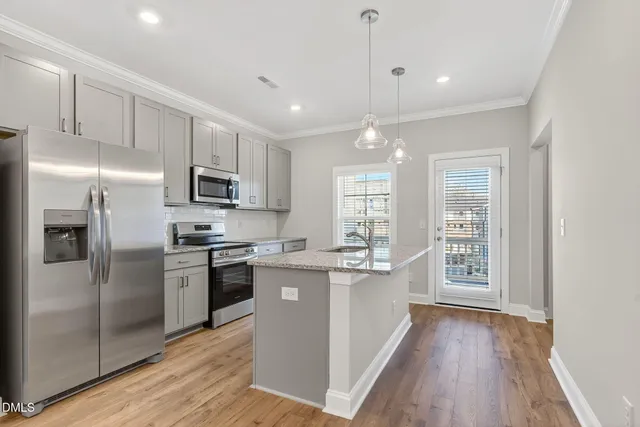 a kitchen with stainless steel appliances granite countertop a refrigerator a sink dishwasher a stove and white countertops with wooden floor