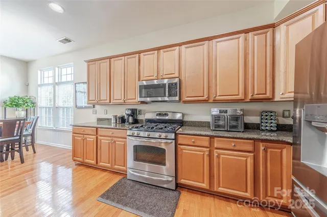 a kitchen with stainless steel appliances granite countertop a stove top oven a sink dishwasher and cabinets with wooden floor