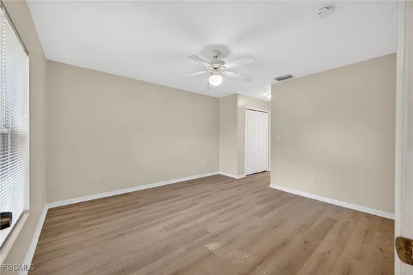 an empty room with wooden floor and fan