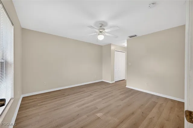 an empty room with wooden floor and fan