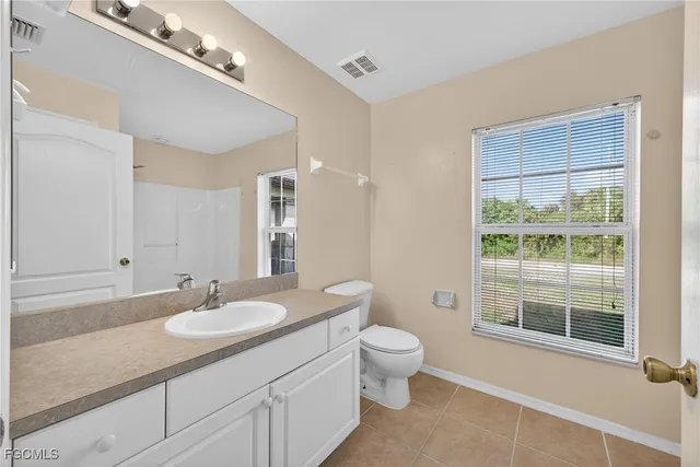 a bathroom with a granite countertop sink a toilet a mirror and a tub