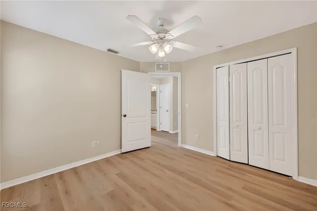 an empty room with wooden floor closet fan and windows