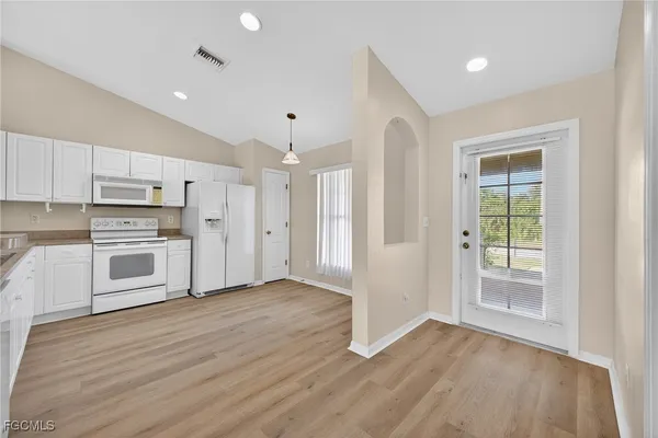 a view of a kitchen with wooden floor and electronic appliances