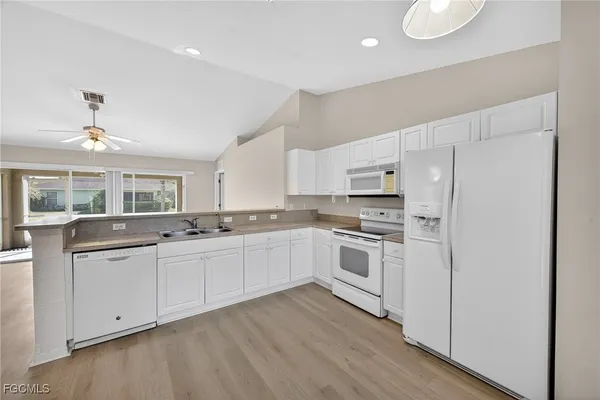 a kitchen with white cabinets and white appliances