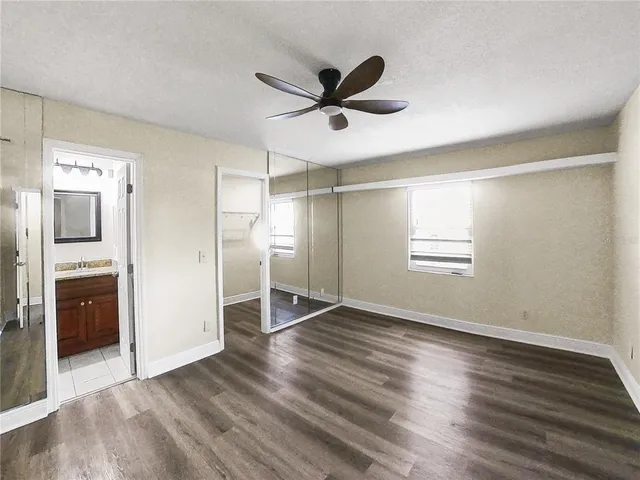 a view of empty room with wooden floor and ceiling fan