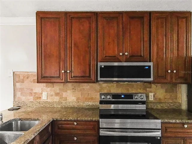 a kitchen with granite countertop wooden cabinets and stainless steel appliances